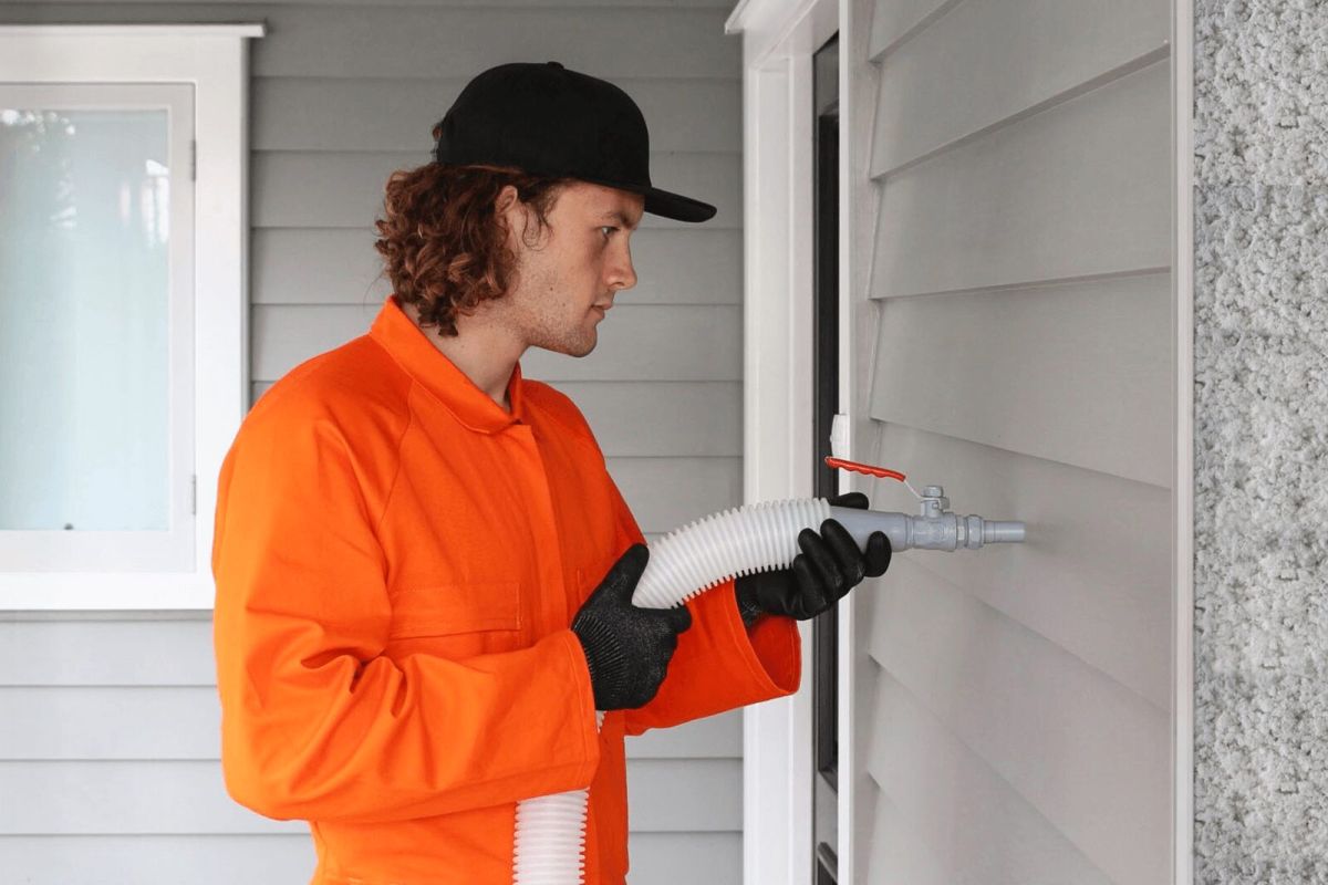 Man installing wall insulation through external wall